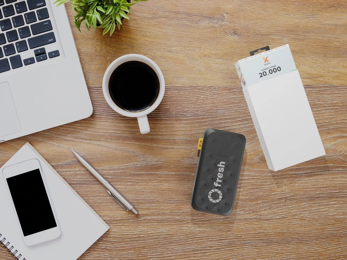 Branded power bank and notebook on a desk next to a laptop